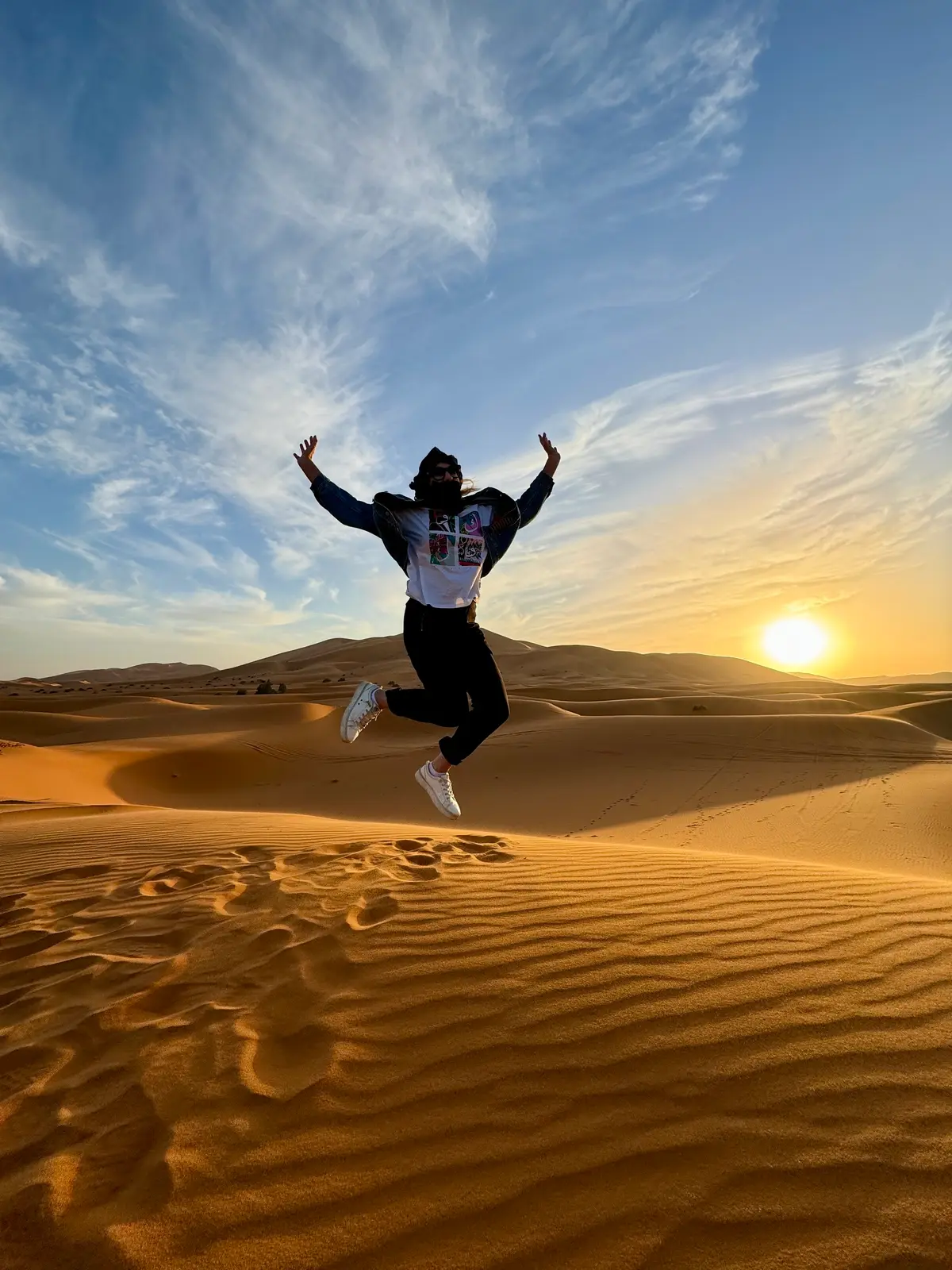 Julie Hartigan jumping on a Sahara sand dune at sunset